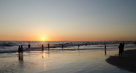 Fototapeta premium Beachgoers watching sunset at Newport Pier