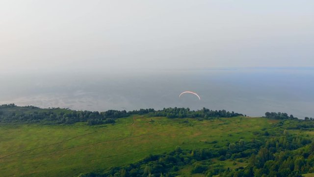 Top view of the green terrain and the parawing flying over it
