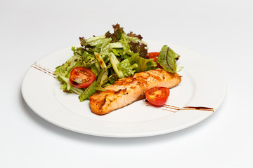 salmon steak with vegetables on a white plate