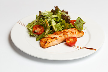 salmon steak with vegetables on a white plate