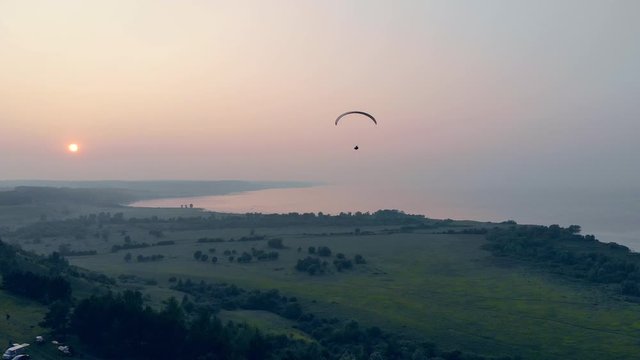 Waterscape with green plains and the paraplane flying along