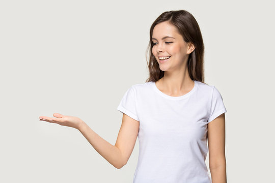 Smiling young woman show blank copy space on hand