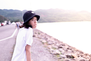 asian Woman wear hat siting in the large lake and mountains in the background ,copy space