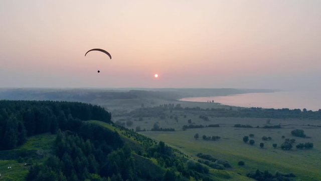 Parasailing vehicle is floating across the sunset horizon
