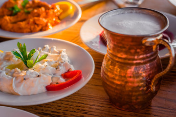 traditional turkish appetizers on table in evening sun light and ayran in a copper glass