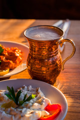 traditional turkish appetizers on table in evening sun light and ayran in a copper glass