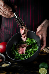 Cooking food fresh diet keto salad with beef meat and fruits on black background.