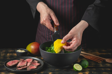 Cooking food fresh diet keto salad with beef meat and fruits on black background.