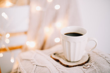 Top view of cup of coffee with a knitted beige plaid on background. Autumn and winter, leisure concept. Flat lay