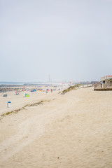 View of pedestrian wooden path on beach, people walking and people taking sunbath on beach