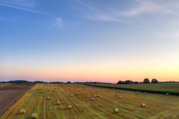 Field of stubble with haystacks early morning. August countryside landscape. Masuria, Poland...