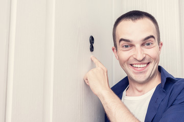 Happy man next to front door, man looked through the peephole of the front door, male rejoices at...