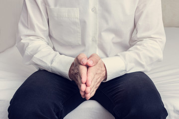 Obraz premium Man sitting on the bed and quietly waiting for someone, man's hands, cropped image, close-up, toned