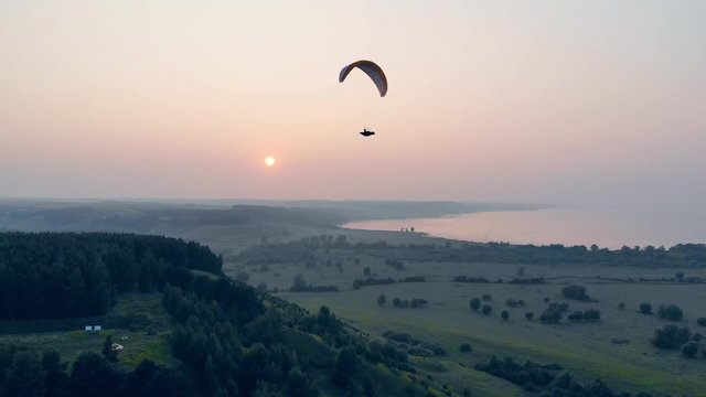 A person in the paraplane is flying high above the ground