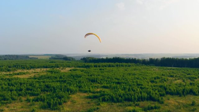 Paraplane is flying over the green plains