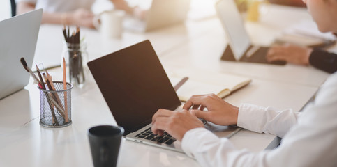 Close-up view of asian businessman working on her project while typing on laptop