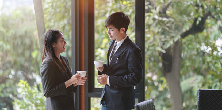 Young professional asian business partner having coffee break and chatting