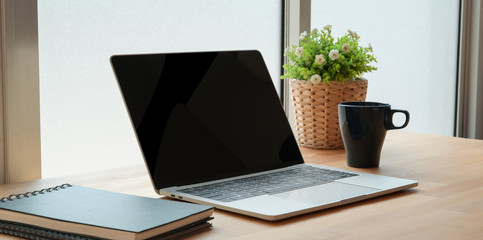 Open laptop computer with office supplies on wooden table