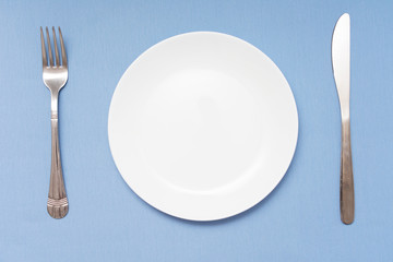 Cutlery set with plate. Dish, fork and knife, copy space, blue background, closeup, top view