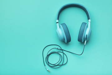 Turquoise headphones on a colored background. Music concept with copyspace. Colored headphones isolated