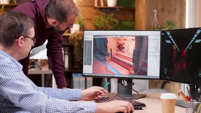 Team of graphic designers talking about the level of a new video game looking at computer display.