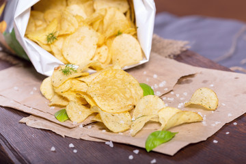 Potato chips with salt and greens on a table in a pub on a background of beer. Chips with greens as a snack to beer. October Beer Fest.