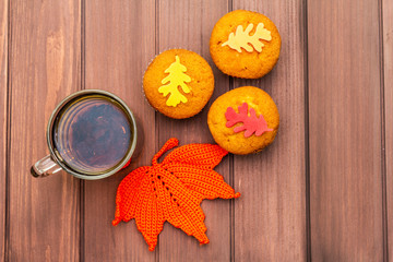 Hot autumn drink. Black tea with cupcakes, colorful leaves