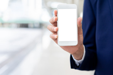 close up businessman hand holding smartphone with isolated mockup blank white screen (for your content) at blur outdoor city building  background foe business and technology and marketing design 