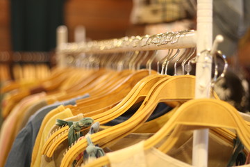 clothing on​ wooden​ hanger​ at​ night​ market.​ Sensitive focus​ the​ wood​en​ hanger.​blur​ hanger​ background.