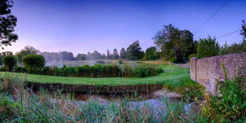 Misty dawn light on Stoke Charity village pond and St Michael's Church, Hampshire, UK