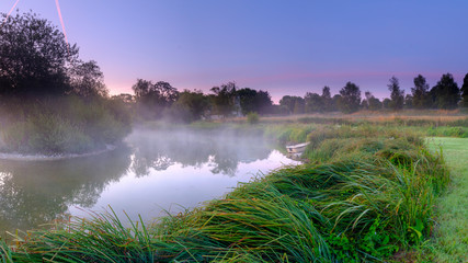 Misty dawn light on Stoke Charity village pond and St Michael's Church, Hampshire, UK