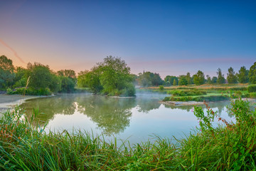 Fototapeta na wymiar Misty dawn light on Stoke Charity village pond and St Michael's Church, Hampshire, UK