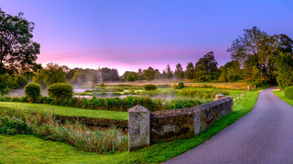 Misty dawn light on Stoke Charity village pond and St Michael's Church, Hampshire, UK
