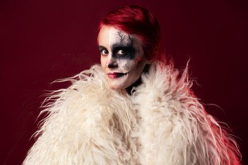 Woman with halloween makeup and red hair wearing white faux fur