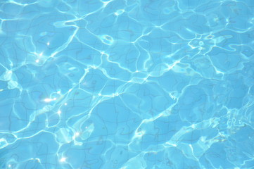 Swimming pool bottom caustics ripple and flow with waves background. Summer background. Texture of water surface.