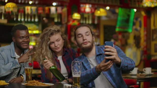 Happy male friends taking selfie and drinking beer at bar or pub. People, leisure, friendship, technology and party concept - happy male friends taking selfie.