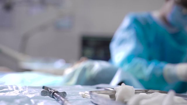 Serious surgery in a dental clinic. The surgeon implants dentures to the patient. The conditions for perfect style are met.