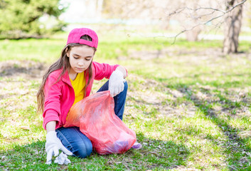 Young volunteer picks up plastic bottles in the trash bag. Volunteer and ecology concept. Empty space for text