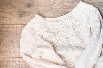 White knitted sweater on a wooden grey table, top view. Flat lay, copy space