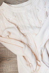 White knitted sweater on a wooden grey table, top view. Flat lay, copy space