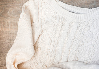 White knitted sweater on a wooden grey table, top view. Flat lay, copy space
