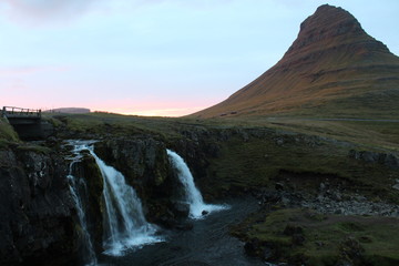 Berghang im Sonnenuntergang mit kleinem Wasserfall davor