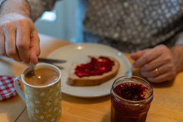 A man stir the coffee eating swiss breakfast