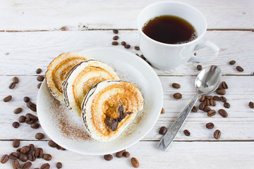 Cup of coffee on a white wooden table and a cake