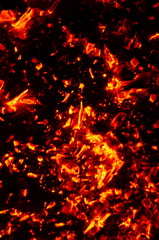Fototapeta na wymiar Actively smoldering embers of fire. Background of burning hot coals. Flicker of burning coals at night