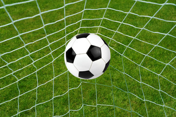 Fototapeta na wymiar Goal. Soccer ball in net with grass background.