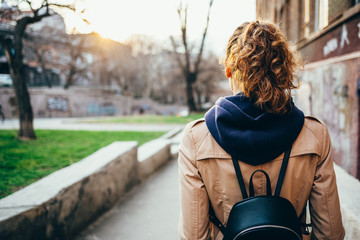 Young woman in a beige coat with a backpack