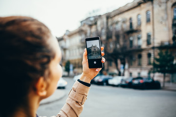 Young woman in a beige coat photographs