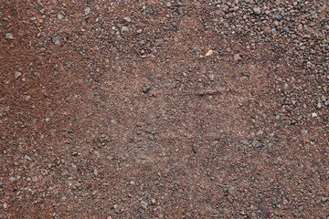 Detail of surface texture with small pebble rock on dirty ground.