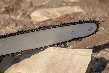 Steel chain chainsaw. sawing firewood outdoors.